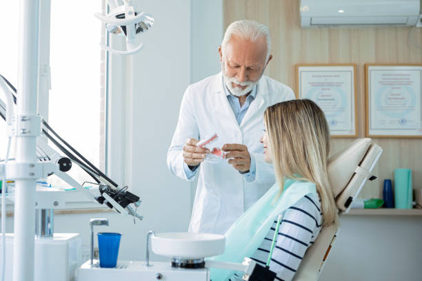 istock Senior dentist showing teeth model to young patient 1400828837