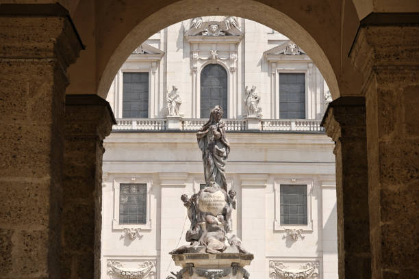 Salzburg, Salzburg - Austria - 06-16-2021: Salzburg Residenzplatz and fountain with horses, dolphins and Triton under a clear sky, next to the historic cathedral