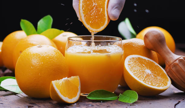 frutas de color amarillo anaranjado y zumo de naranja fresco. exprimiendo la naranja fresca. - freshly squeezed fotografías e imágenes de stock