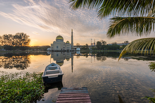 a beautiful morning sunrise at As-Salam Mosque Puchong, with a boat as foreground in lake
