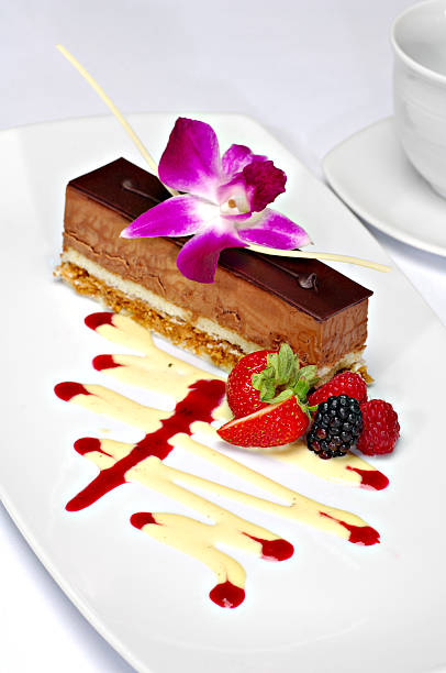 Plated chocolate mousse dessert Beautifully plated chocolate mousse cake garnished with a purple orchid, strawberry, blackberry and raspberry. A zigzag of white chocolate and strawberry sauce completes the plate. plated chocolate dessert stock pictures, royalty-free photos & images