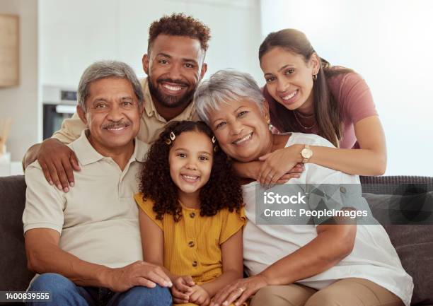 Portrait Of Mixed Race Family With Child Enjoying Weekend In Living Room At Home Adorable Smiling Hispanic Girl Bonding With Grandparents Mother And Father Happy Couples And Child Sitting Together Stock Photo - Download Image Now