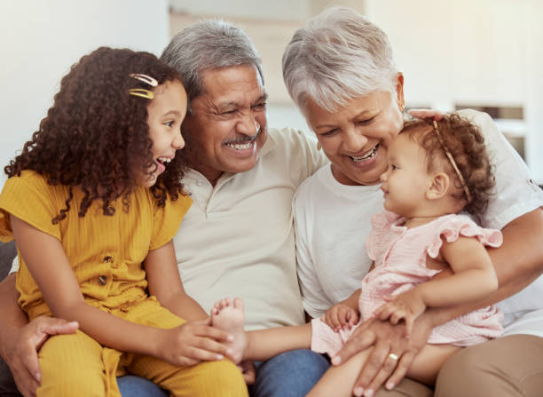 Mixed race grandparents enjoying weekend with granddaughters in home living room. Adorable smiling hispanic girls bonding with grandmother and grandfather. Happy seniors and children sitting together Mixed race grandparents enjoying weekend with granddaughters in home living room. Adorable smiling hispanic girls bonding with grandmother and grandfather. Happy seniors and children sitting together human relationship stock pictures, royalty-free photos & images