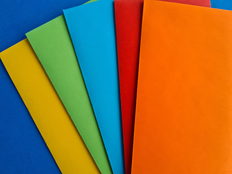 Multi-colored envelopes and paper on a blue background. Color paper concept