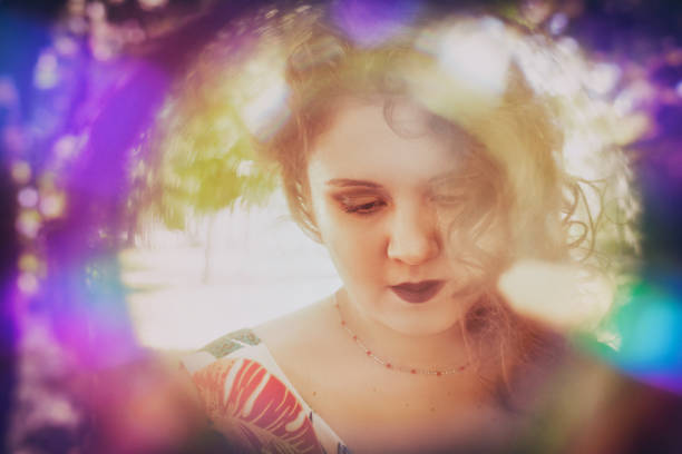 Young woman headshot portrait in rainbow frame, looking down