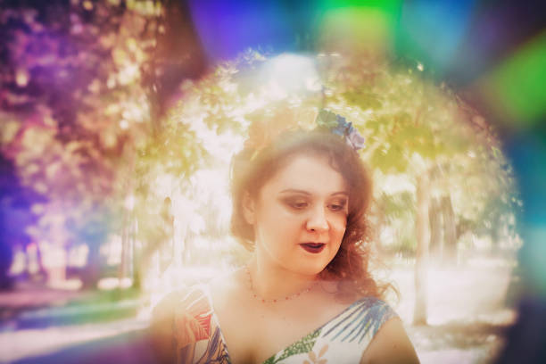 Young woman headshot portrait in rainbow frame, looking down and smiling