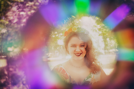 Young woman headshot portrait in rainbow frame, smiling widely at camera