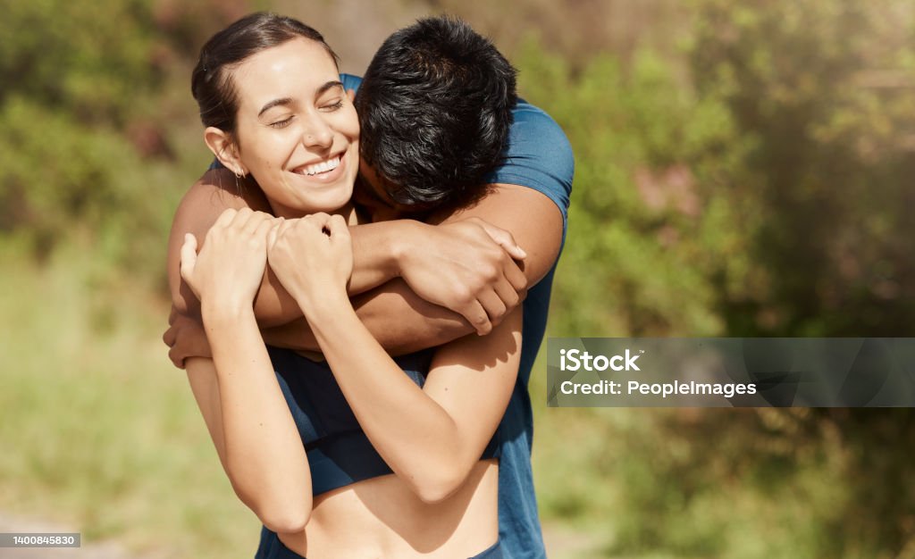 Affectionate young interracial couple taking a break from exercise and run outdoors. Loving man hugging arm around woman while motivating each other towards better health and fitness 20-24 Years Stock Photo