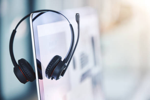 gros plan d’un casque accroché à un écran de bureau d’ordinateur dans un bureau vide d’un centre d’appels. service d’assistance opérationnel pour le service à la clientèle et le soutien aux ventes. agents de télémarketing offrant de l’a - casque téléphonique photos et images de collection