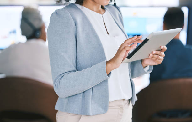 istock Closeup of mixed race businesswoman browsing on a digital tablet device while working in a call centre with her colleagues in the background. Female manager and supervisor planning online with smart apps for customer service support 1400848464