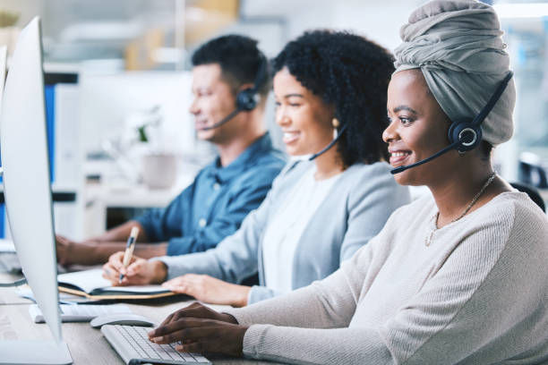 istock African american female call centre telemarketing agent working on computer alongside colleagues in an office. Group of diverse consultants troubleshooting solution for customer service and sales support 1400848648