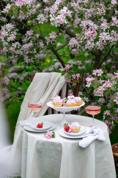 istock Table set on a white tablecloth on a sunny day, cherry blossom, cupcake, wine. Outdoor, picnic, brunch, spring mood. Soft focus 1400848803