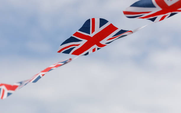 istock Union Jack bunting flags flying in the wind with a sky background 1400848816