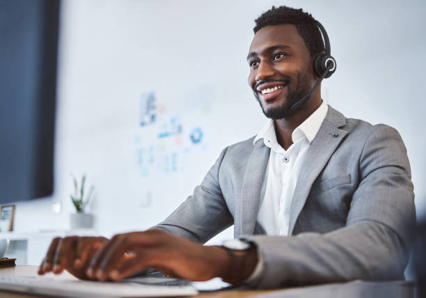 istock One happy young african american call centre telemarketing agent talking on a headset while working on computer in an office. Confident friendly male consultant operating helpdesk for customer service and sales support 1400848825
