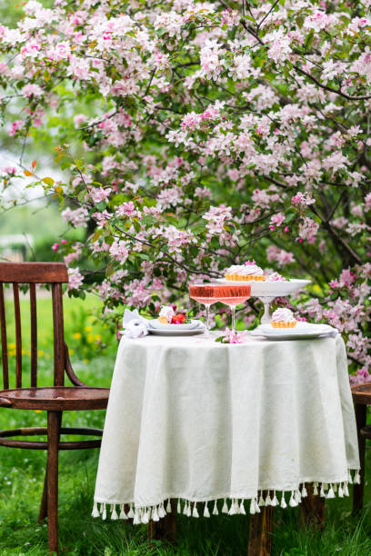 istock Festive spring romantic table setting with dessert in blossom garden. Vertical 1400848852