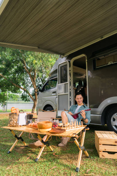 istock happy Man sitting outside camp van and playing guitar 1400852386