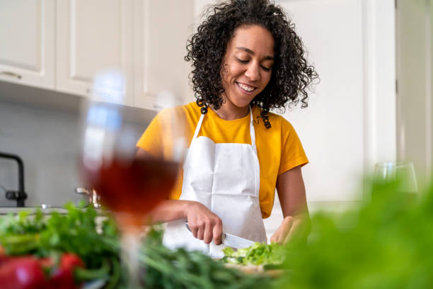 istock Young happy woman in modern kitchen chopping salad 1400852725