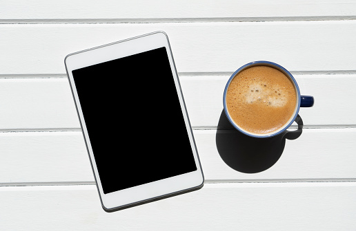 cup of coffee with digital tablet on wooden table