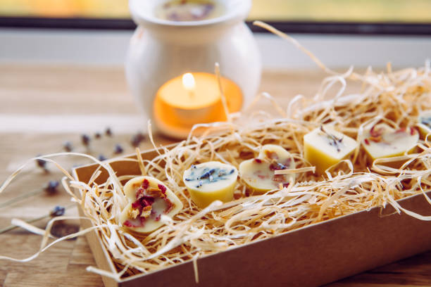 cadeau naturel fait à la main, mini cire parfumée fond avec des herbes de fleurs séchées pour la décoration dans une boîte cadeau en carton avec et une charge de bois déchiqueté. vue latérale, lumière naturelle dans la maison. - coconut oil lamps photos et images de collection
