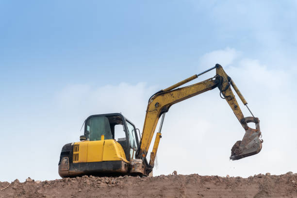 excavator digging and loading dirt at the construction site with empty sky for copy space. stock photo