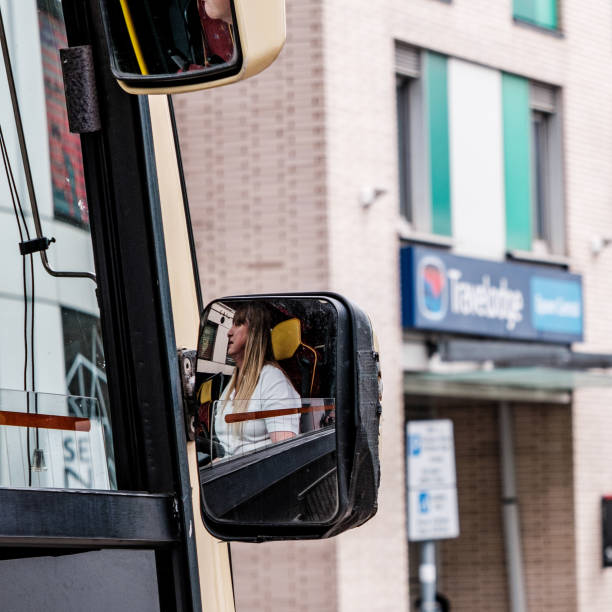 Woman Bus Driver Reflection In Her Drivers Rear View Mirror Epson Surrey, London UK, June 03 2022, Woman Bus Driver Reflection In Her Drivers Rear View Mirror Passing Travellodge Hotel surrey hotel southeast england england stock pictures, royalty-free photos & images