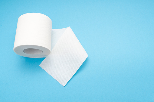 White blank roll of toilet paper with long sheet on blue background, top view