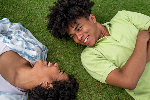 Latin couple lying on the grass - stock photo
