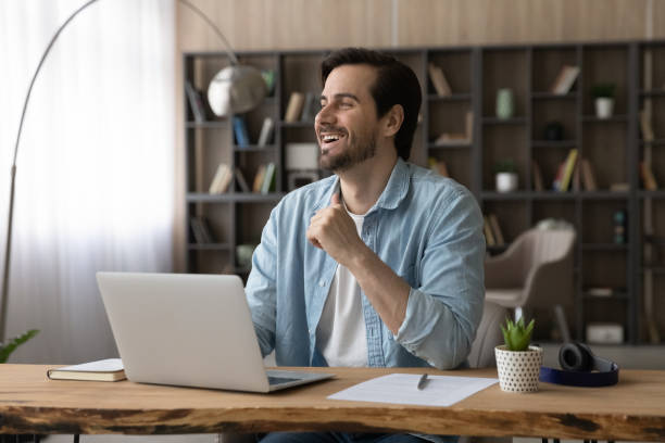 istock Glad young male sit at desk look above pc screen 1400864415
