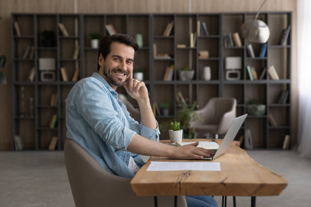 portrait d’un jeune homme travaillant au bureau à domicile par pc - looking at camera smiling desk isolated photos et images de collection