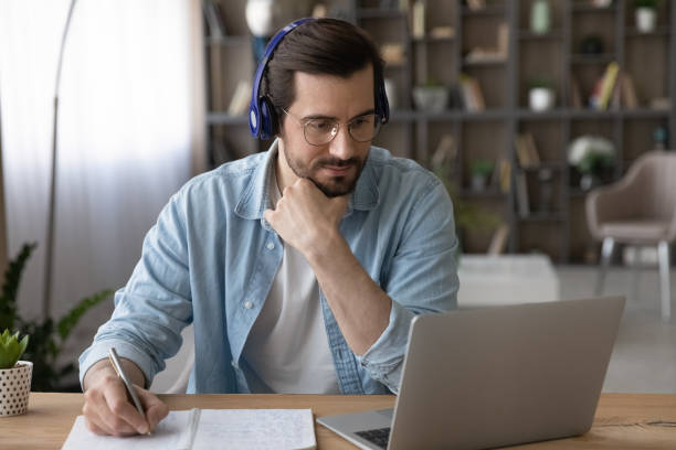 istock Focused male student in headphones look on pc do homework 1400865187
