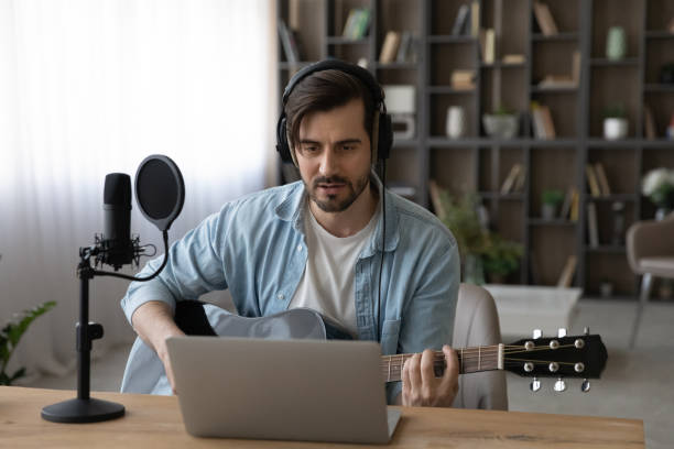 istock Focused young guy give online acoustic guitar lesson before laptop 1400865201