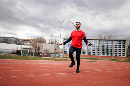 Fit man jumping rope during his sports training outdoors