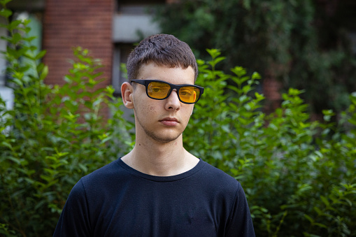 Portrait of Caucasian teenage boy, wear sunglasses and black shirt outdoor