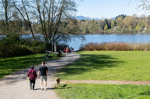 Burnaby, BC, Canada - April 18 2021 : People walking on the Deer Lake Park trail. Burnaby, BC, Canada.