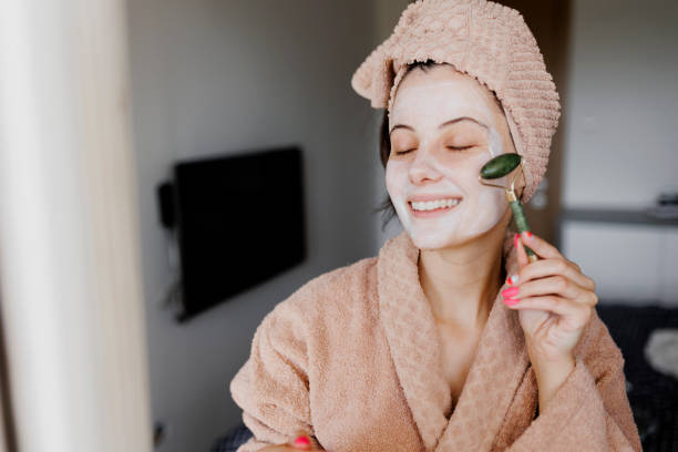 istock Woman using jade roller on her face at home. Young girl massaging face by jade roller. Self-care facial massage, anti-aging lifting skincare procedure 1400870204