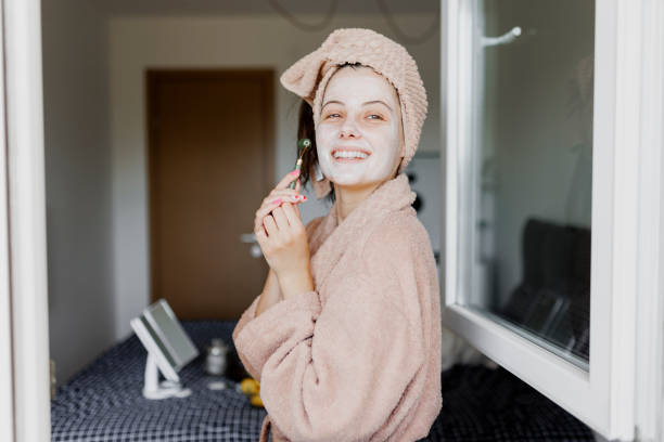istock Woman using jade roller on her face at home. Young girl massaging face by jade roller. Self-care facial massage, anti-aging lifting skincare procedure 1400870894