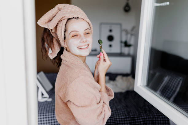 istock Woman using jade roller on her face at home. Young girl massaging face by jade roller. Self-care facial massage, anti-aging lifting skincare procedure 1400871232