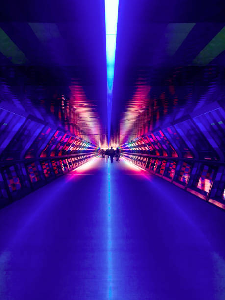Colourful and vibrant pedestrian tunnel in London Colourful and vibrant pedestrian tunnel at Canary Wharf in London. Silhouette of people are seen at the distance at the other end of the tunnel. incidental people photos stock pictures, royalty-free photos & images