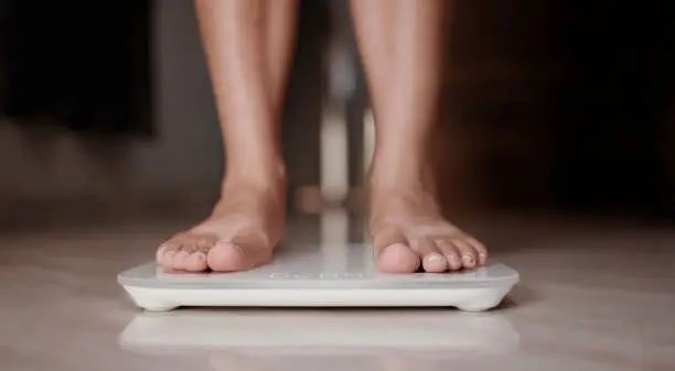 Photo of Woman on scales measure weight. Female dieting checking BMI weight loss.