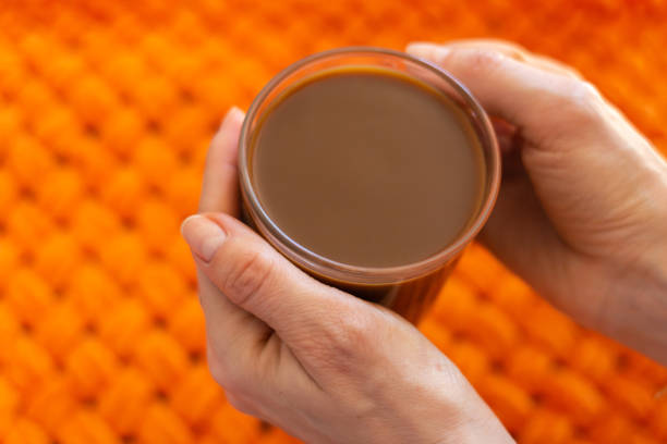 Girl holding coffee cup on orange background. Hands holding cup of morning coffee. Latte in cafe. Cappuccino cup. Espresso with milk. Hot drinks. Relax with coffee. Breakfast concept.