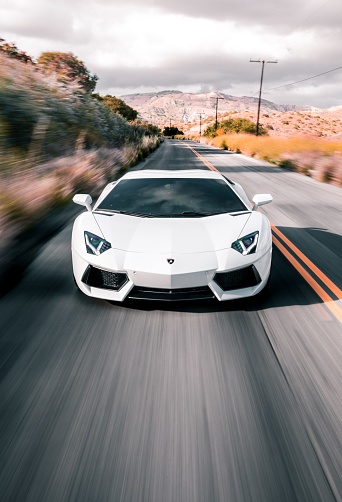 LA, CA, USA\n5/5/2022\nWhite Lamborghini Aventador driving on a road by itself with the double yellow line on its right
