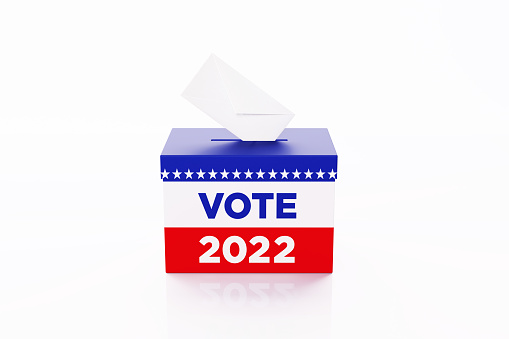 Vote 2022 written ballot box textured with American flag. Isolated on white background. A vote envelope is entering into the ballot box. Horizontal composition with copy space. Great use for referendum and presidential elections related concepts. Clipping path is included.