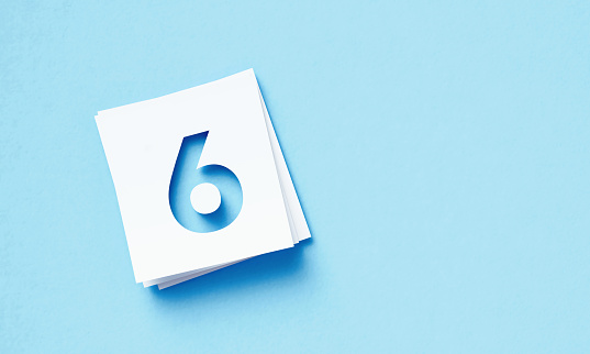 White Adhesive Notes With Cutout Number 6 Sitting Over Blue Background
