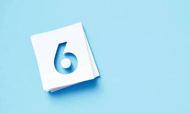 Photo of White Adhesive Notes With Cutout Number 6 Sitting Over Blue Background