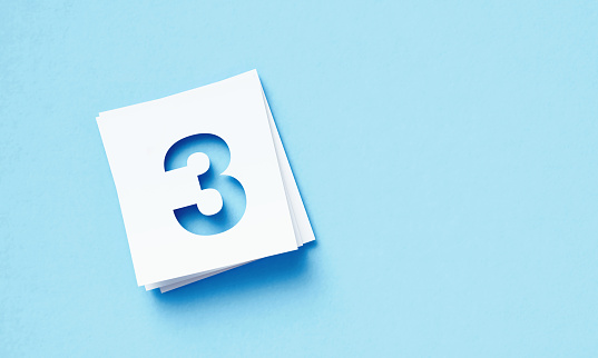 White adhesive notes with cutout number 3 sitting on blue background. Horizontal composition with copy space.