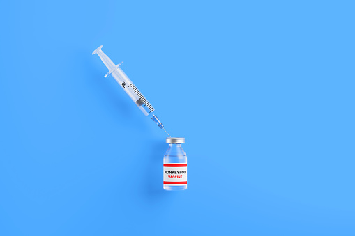 Monkeypox vaccine and syringe on blue background, Horizontal composition with copy space. Monkeypox vaccine concept.