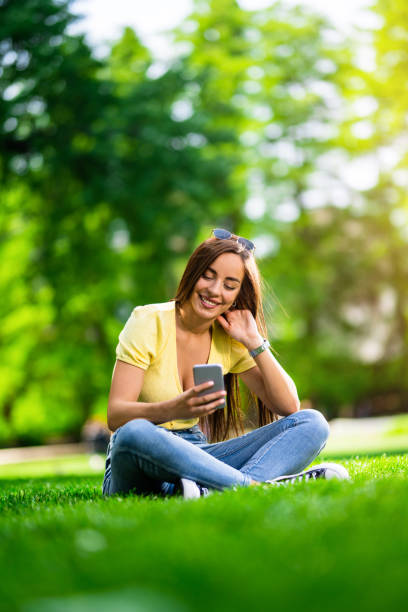 istock Happy young woman using phone in the park. 1400882435