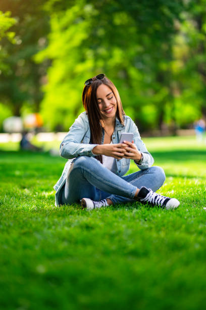 istock Happy young woman using phone in the park. 1400882492