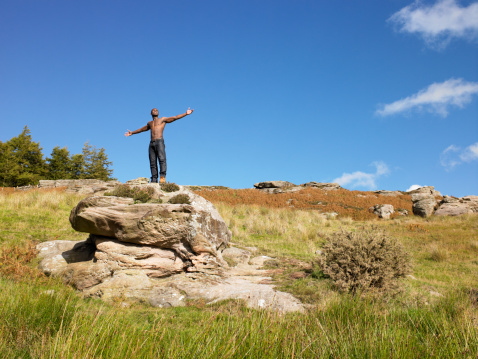 Young man in the countryside standing on a boulder posing