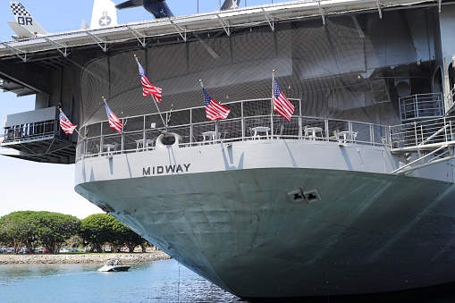 A view of Pearl Harbor, Hawaii, from the back of a navy launch docked at the U.S.S. Arizona memorial. The American flag is at the rear of the launch; in the distance on the right is the U.S.S. Missouri, on which the surrender of Japan was signed in 1945.